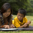 Asian mother reading book to son