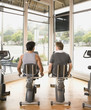 Rear view of two men using exercise bikes
