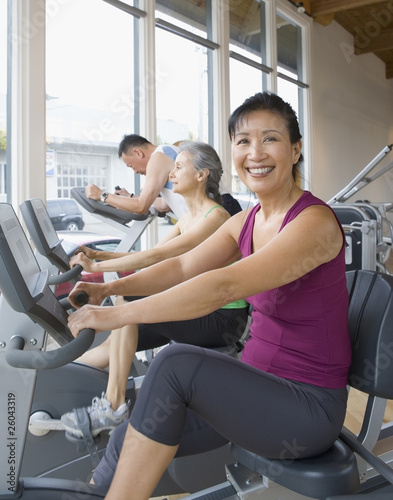 Photo: Asian woman riding exercise bike in health club Asian woman riding exercise bike in health club