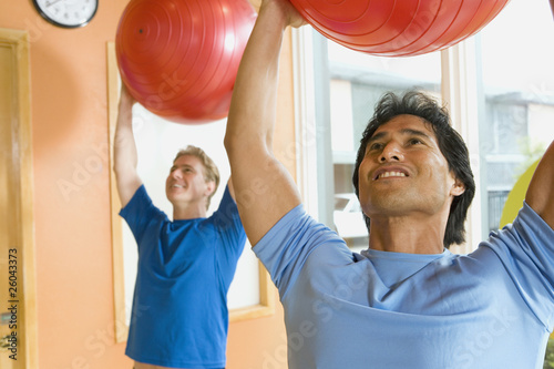 Photo: Two men exercising with fitness balls in health club Two men exercising with fitness balls in health club