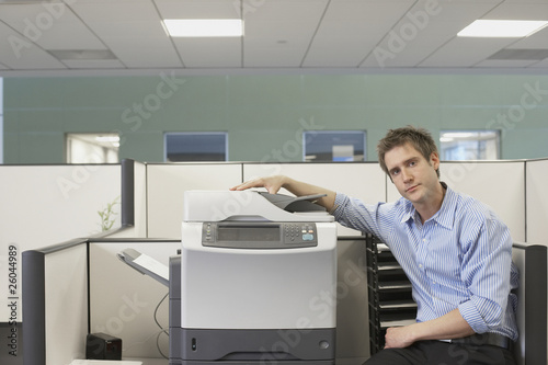 Foto: Businessman sitting next to copy machine Businessman sitting next to copy machine