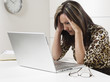Photo: Hispanic businesswoman looking at laptop with head in hands Hispanic businesswoman looking at laptop with head in hands