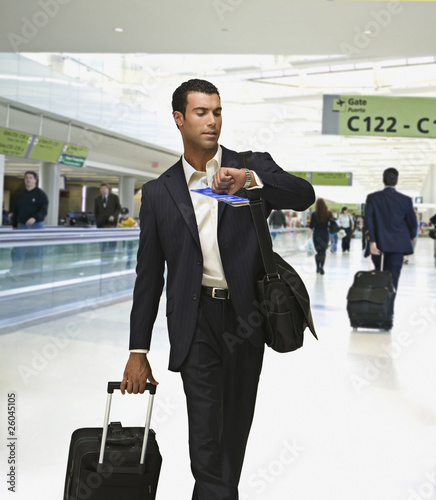 Photo: Hispanic businessman checking time in airport Hispanic businessman checking time in airport
