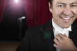 Hispanic man in tuxedo adjusting tie backstage