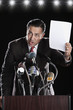 Hispanic man holding paper at press conference podium