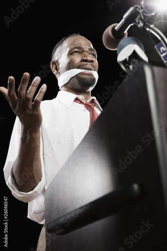 Photo: African American man at podium with gag in mouth African American man at podium with gag in mouth