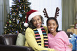 African woman and granddaughter in santa hat and antler headband