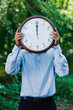 Hispanic businessman holding clock in forest