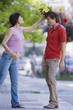 Hispanic woman hitting boyfriend with bouquet of flowers
