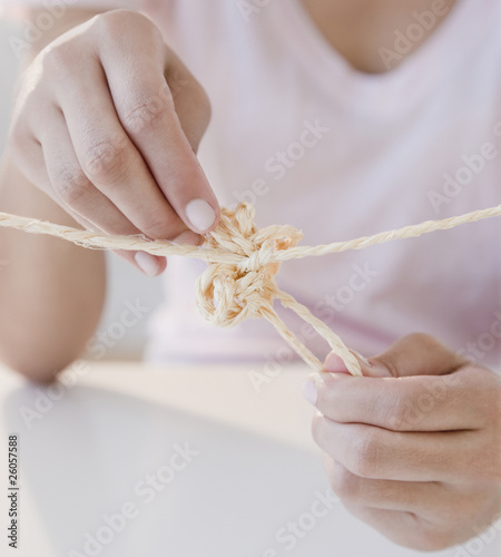 Photo: Woman tying knot in rope Woman tying knot in rope
