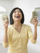 Smiling Filipino woman holding money and looking up