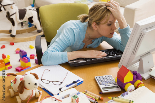 Photo: Frustrated Hispanic woman at desk surrounded by toys Frustrated Hispanic woman at desk surrounded by toys