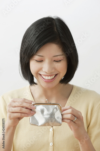 Photo: Filipino woman looking into wallet and smiling Filipino woman looking into wallet and smiling