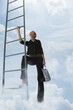 Mixed race woman climbing ladder in clouds