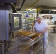 Kitchen porter pushes a trolley of pastries