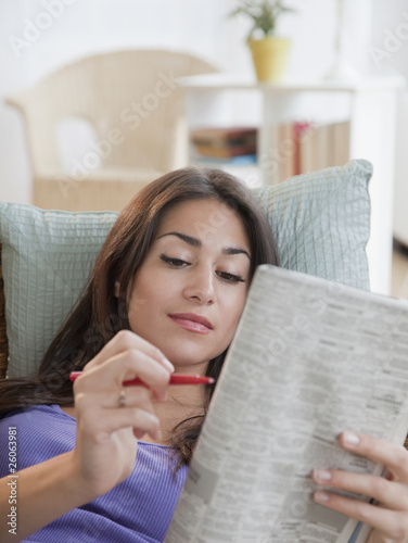 Photo: Hispanic woman doing newspaper crossword puzzle Hispanic woman doing newspaper crossword puzzle