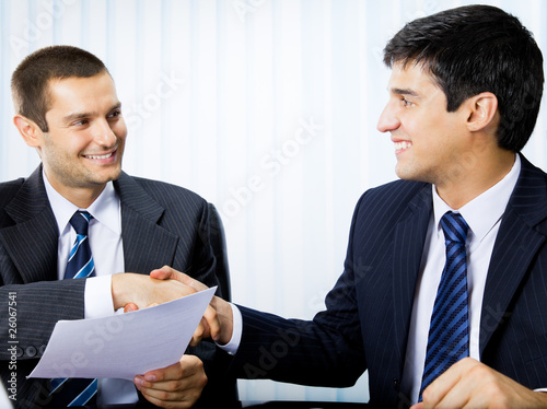 Foto: Businesspeople, or businessman and client, with document Businesspeople, or businessman and client, with document