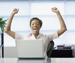 African woman with laptop celebrating