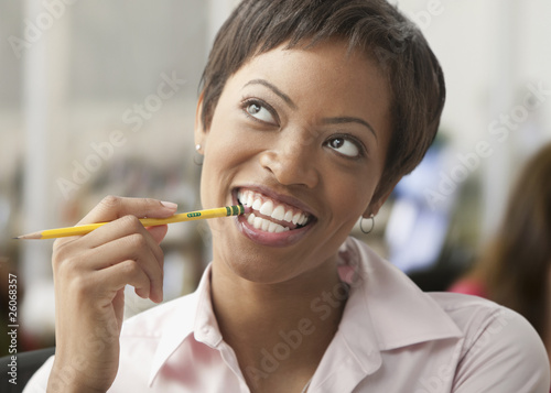Photo: African woman biting eraser of pencil and looking up African woman biting eraser of pencil and looking up