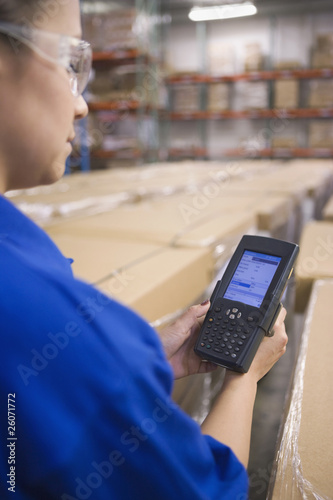 Photo: Hispanic woman using tracking device in warehouse Hispanic woman using tracking device in warehouse