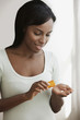 African woman holding prescription bottle and pills