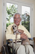 Elderly Hispanic man in wheelchair holding dog