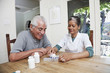 Home nurse filling daily vitamin container for elderly man