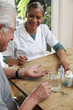 Home nurse giving elderly man vitamins