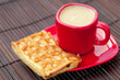 cup of cappuccino wafers and coffee beans on a bamboo mat