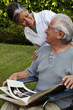 Home nurse and elderly man looking at photograph album