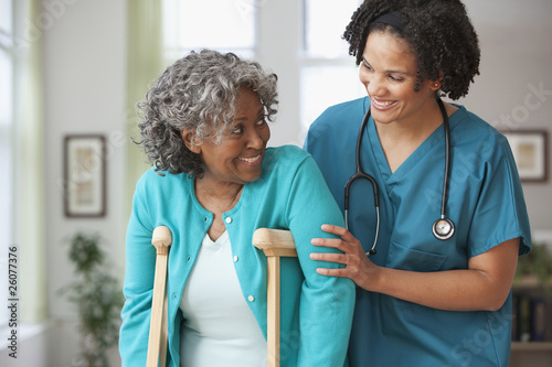Photo: African home nurse helping woman on crutches African home nurse helping woman on crutches