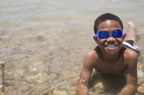Photo: African boy wearing goggles and laying in shallow lake African boy wearing goggles and laying in shallow lake