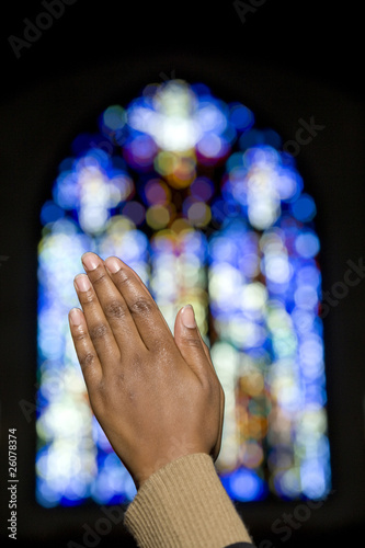 Photo: African woman's hands clasped in prayer in front of stained glass window African woman's hands clasped in prayer in front of stained glass window