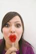 Hispanic woman with heart-shaped lollipop