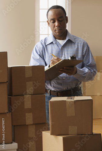 Photo: African man with clipboard and moving boxes African man with clipboard and moving boxes
