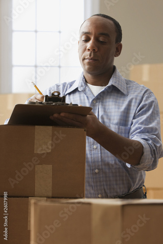 Photo: African man with clipboard and moving boxes African man with clipboard and moving boxes