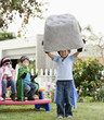 Korean boy as superheros lifting large boulder