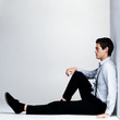 Thoughtful young man sitting on the floor - Copyspace