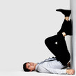 Young man lying on floor with legs up against a wall
