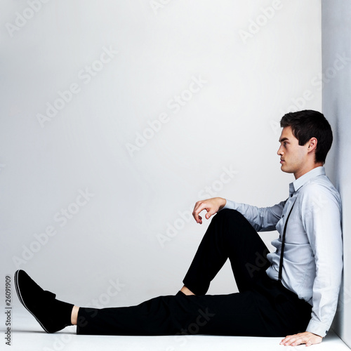 Photo: Thoughtful young man sitting on the floor - Copyspace Thoughtful young man sitting on the floor - Copyspace
