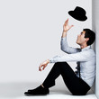 Photo: young man sitting on floor and playing with hat young man sitting on floor and playing with hat