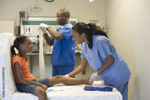 Photo: Doctor and nurse helping girl with injured leg Doctor and nurse helping girl with injured leg