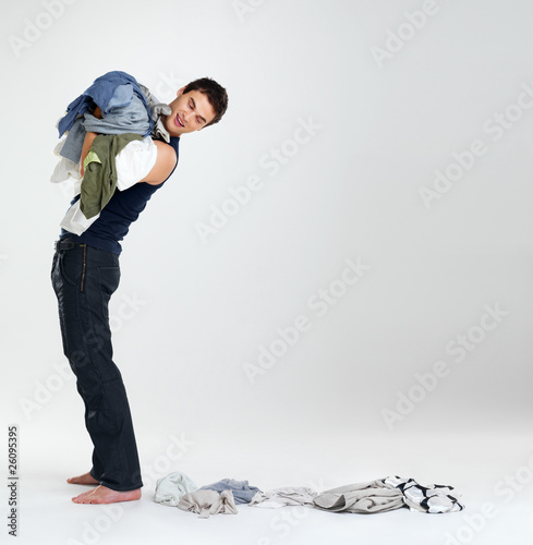 Photo: Happy young man carrying clothes in laundry Happy young man carrying clothes in laundry