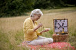 A senior woman sitting on the grass, eating