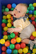 Cute boy playing in a pool of plastic balls