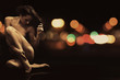 Naked young woman in sensual pose on the street