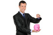 Businessman putting a coin into a piggy bank Businessman putting a coin into a piggy bank