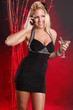 Cute blond in cocktail dress makes a call while having a martini
