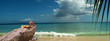 Model is relaxing on tropical beach rock. Panorama.