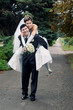 Foto: Smiling groom carrying on his back bride outdoors in park Smiling groom carrying on his back bride outdoors in park